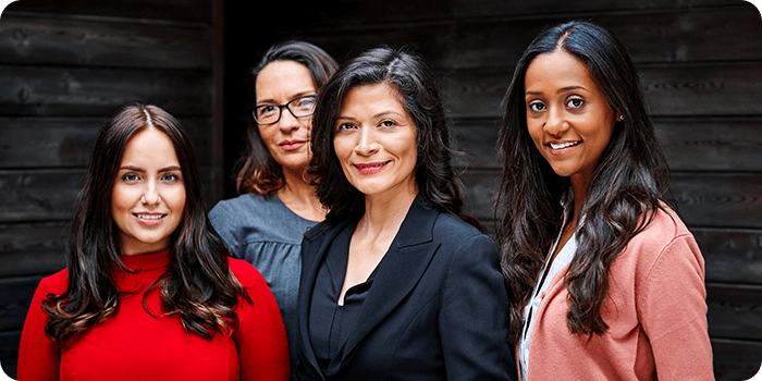 Four smartly dressed women stand facing the camera