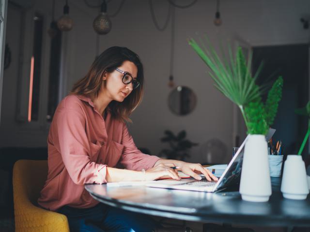 Woman working at a desk with a plant