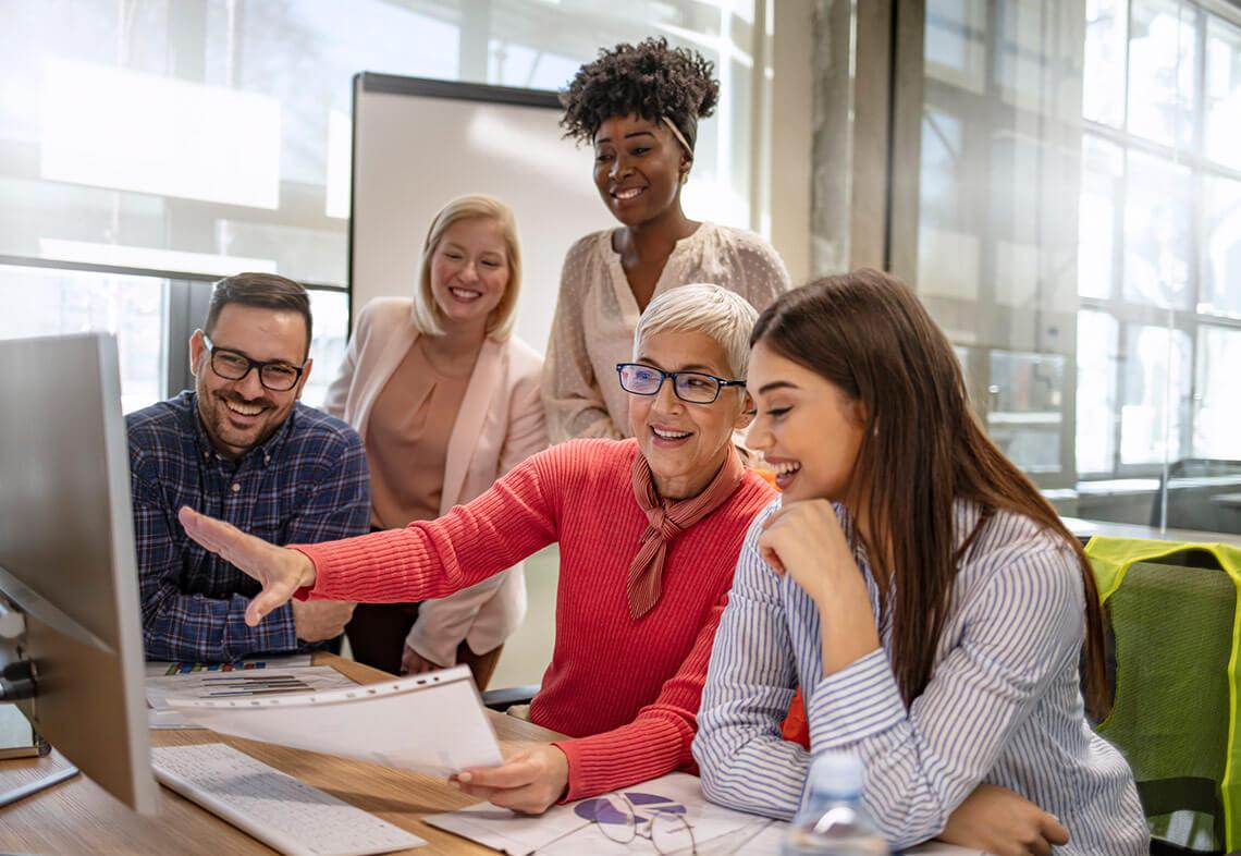 A group of people sit in an office looking at a screen